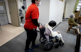 A caretaker wheels an elderly woman after a bath at a day care facility for senior citizens in Tokyo
