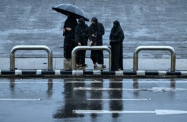 Women wait for a taxi in rainfall in Mumbai on June 23