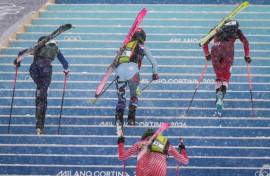 Competitors race uphill in a women's sprint ski mountaineering heat during the Milano Cortina 2026 Winter Olympic Games