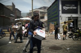 A man carries a box as looting erupted in Catia La Mar in La Guaira State, about 30 km northwest of Caracas, on June 25, 2026