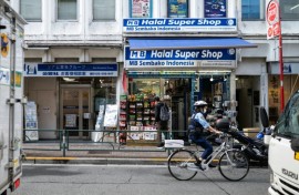 A police officer bikes past a convenience store in the Okubo–Shin area in Tokyo, a neighbourhood known for its large immigrant communities