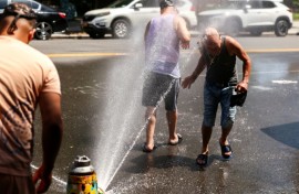 Men cool off at a fire hydrant in the Hamilton Heights neighborhood in Manhattan