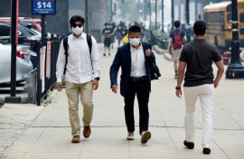 People wear face masks while walking through downtown Chicago as smoke from wildfires burning in Canada blankets the Chicago metropolitan area on July 16, 2026