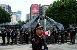 A member of the Secretariat of Citizen Security uses a megaphone to give instructions to personnel evacuated from several buildings following a preventive evacuation in Mexico City