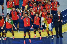 Spain's midfielder #16 Rodri (front C) lifts the trophy with Spain's players next to US President Donald Trump (R) during the final ceremony after the 2026 World Cup