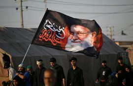 Shiite Muslim pilgrims hold a flag bearing the portrait of Iran's slain supreme leader Ayatollah Ali Khamenei as they march to the Iraqi city of Karbala