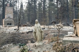 A Virgin Mary statue remains untouched in front of a burned out residential home in the Balboa neighborhood of Spokane, Washington, on August 2, 2026.