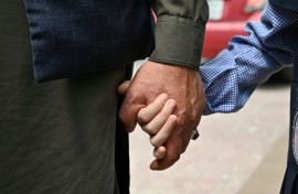 An Afghan father holds his daughter's hand