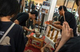 Dozens of bereaved students, parents and teachers queued at a Buddhist temple in Thailand to pray over the body of a 12-year-old girl, one of eight victims of a home and school shooting.