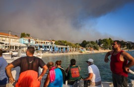 People use small boats to flee a wildfire near the village of Siviri, northern Greece
