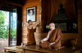 British and Thai Buddhist monk Shaun Chiverton, now known as Ajahn Jayasaro, sits as another monk holds a ceremonial fan in Bangkok