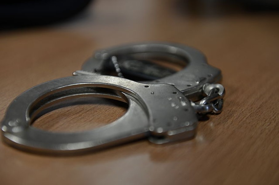 File: A set of handcuffs lying on a desk. Wikimedia Commons/Airman 1st Class Gustavo Castillo