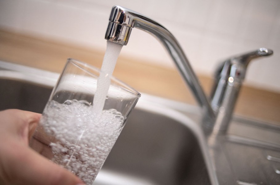 File: A man holds a glass under a running tap. AFP/DPA/Marius Becker