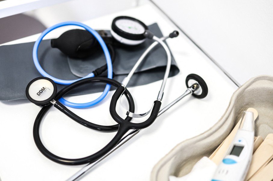 medical instruments including a stethoscope and thermometer as they lie on a table in a doctor's office. AFP/Charly Triballeau