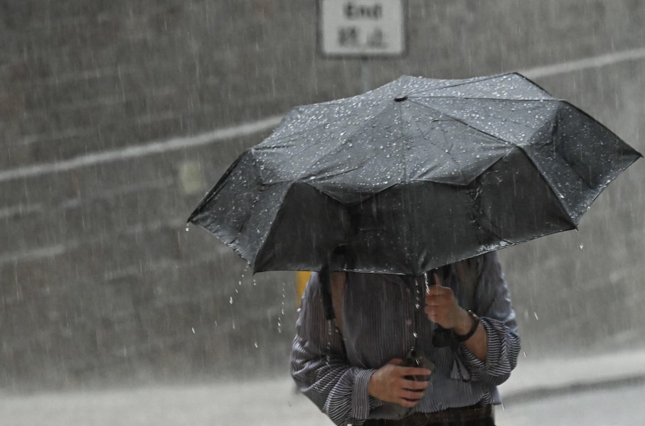 File: A person uses an umbrella to shelter from the heavy rain. AFP/Peter Parks