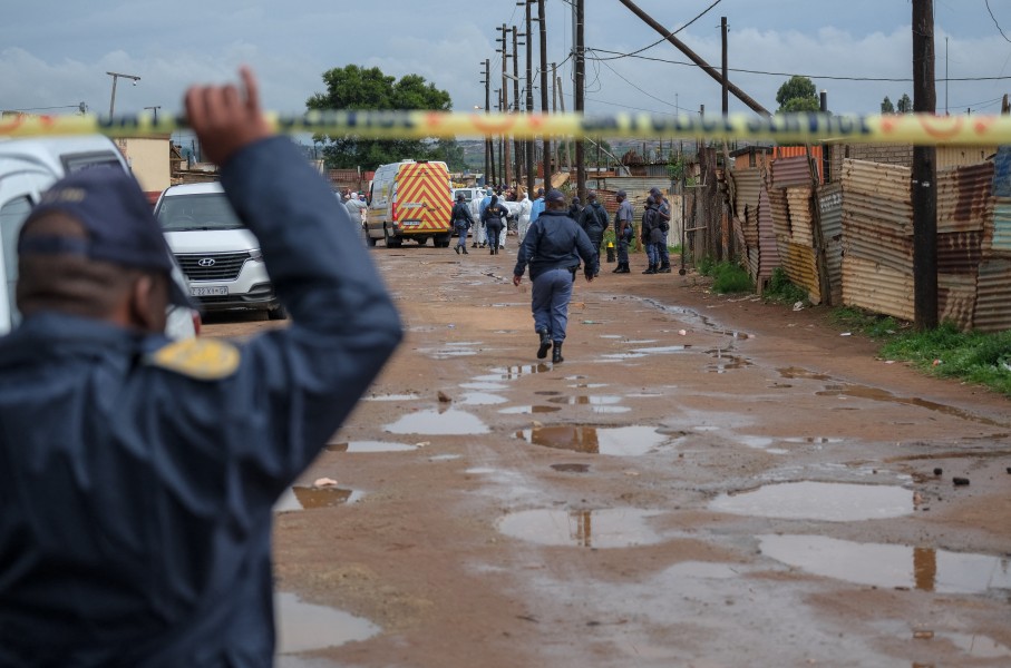 Police officers stand at the scene of an attack at a tavern in Bekkersdal. AFP/Emmanuel Croset