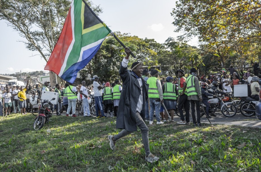 A “March and March” supporter waves the South African flag during a protest march in Durban on May 20, 2026.