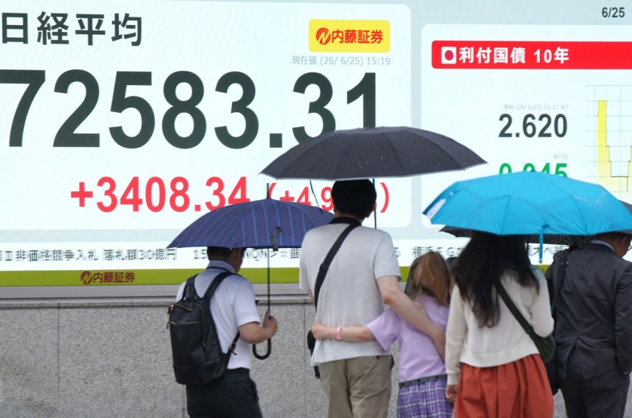 Pedestrians walk past an electronic quotation board displaying the Nikkei Stock Average. AFP/Kazuhiro Nogi