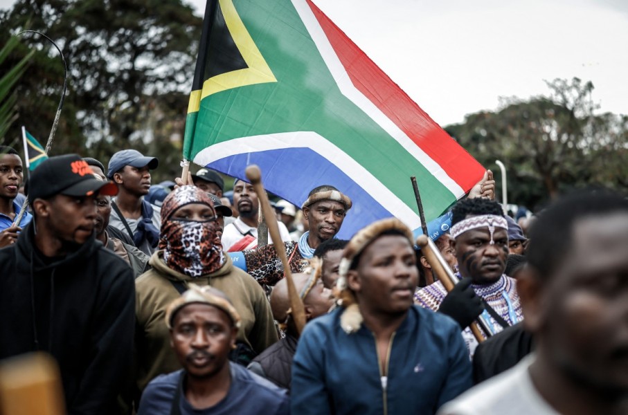 Members of the Zulu regiment known as the ‘Amabutho’ hold a South African flag as they march during a demonstration by the "March and March" movement. AFP/Marco Longari