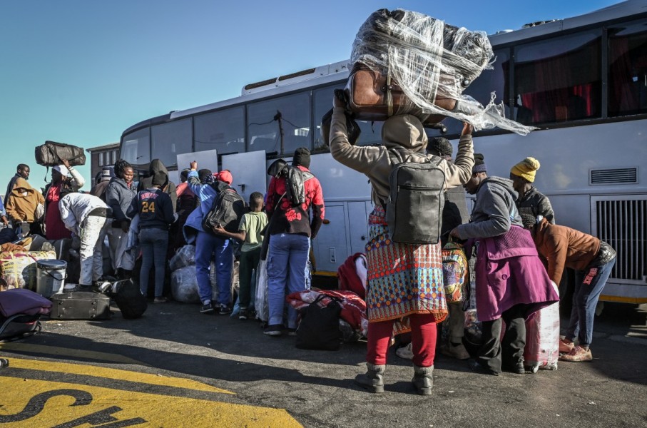 Zimbabwean nationals line up carrying their belongings as they wait to board a bus at a Department of Home Affairs Refugee Reception Centre while awaiting repatriation. AFP/Rodger Bosch