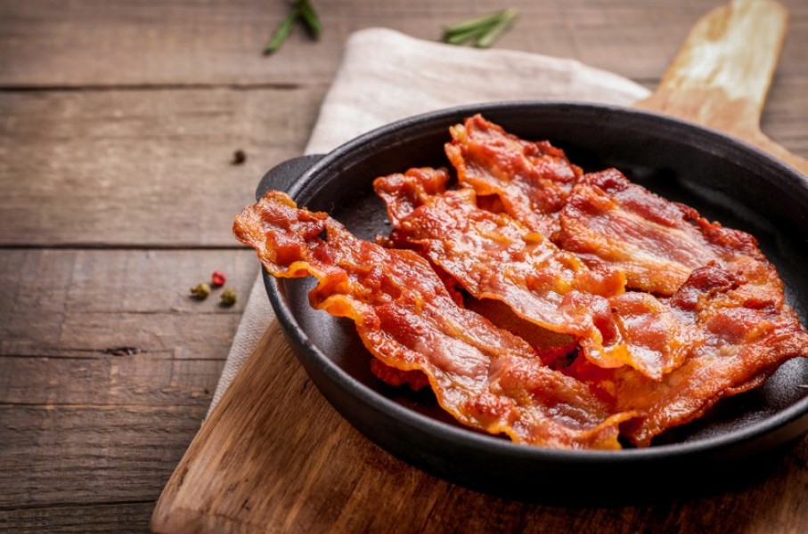 Hot fried crispy bacon slices in a skillet. GettyImages/LumenSt