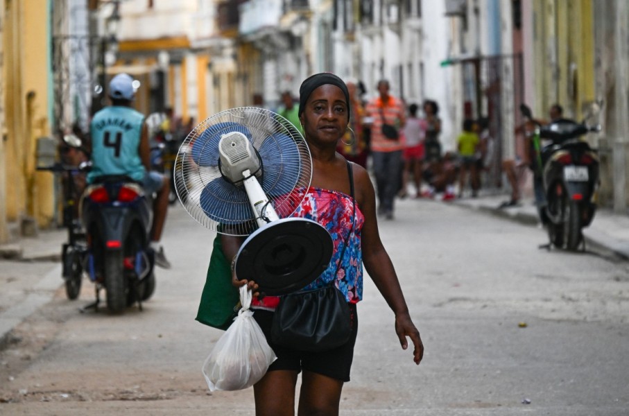 A woman carries a fan along a street in Havana during a nationwide power cut. AFP/Yamil Lage
