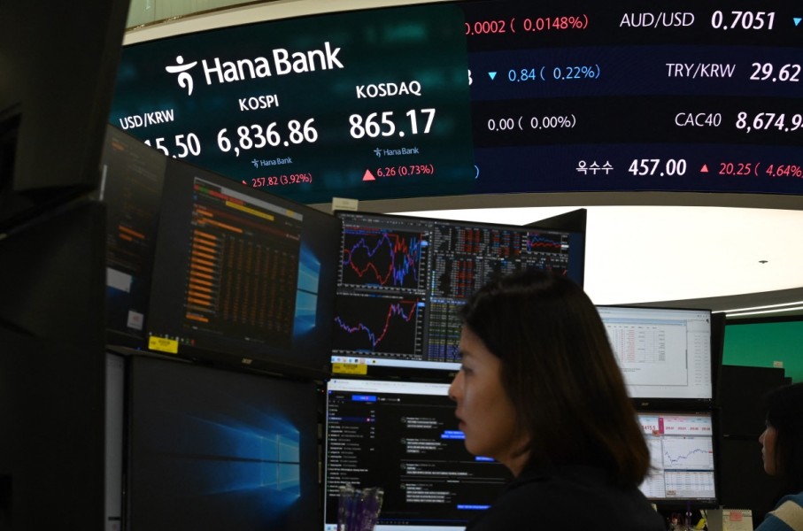 A dealer works near a screen showing South Korea’s benchmark KOSPI stocks index. AFP/Greg Baker