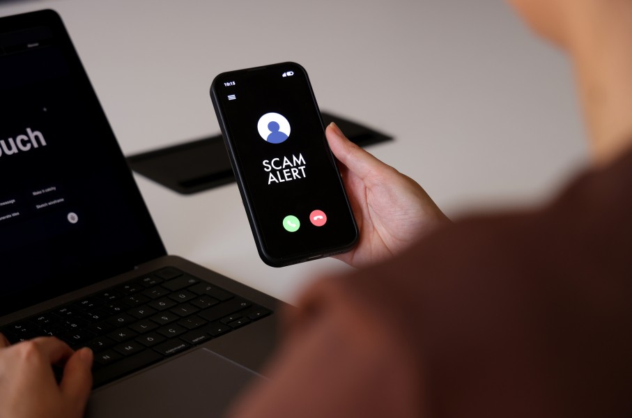 A person holds a smartphone displaying a “Scam Alert” message on an incoming call screen. GettyImages/tolgart