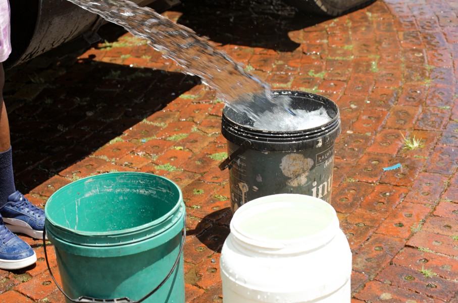Buckets being filled with water from a water tanker.