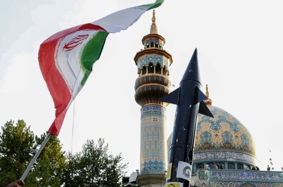 Iranians in central Tehran lift up a flag and the mock-up of a missile during a celebration following Iran's unprecedented attack by missiles and drones on Israel