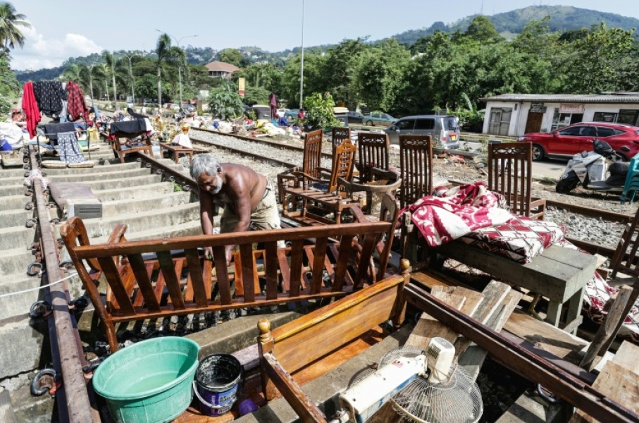 A Sri Lankan flood victim sorts out his belongings by railway tracks in Kandy. The authorities have issued fresh landslide warnings as monsoon storms make hillsides unstable