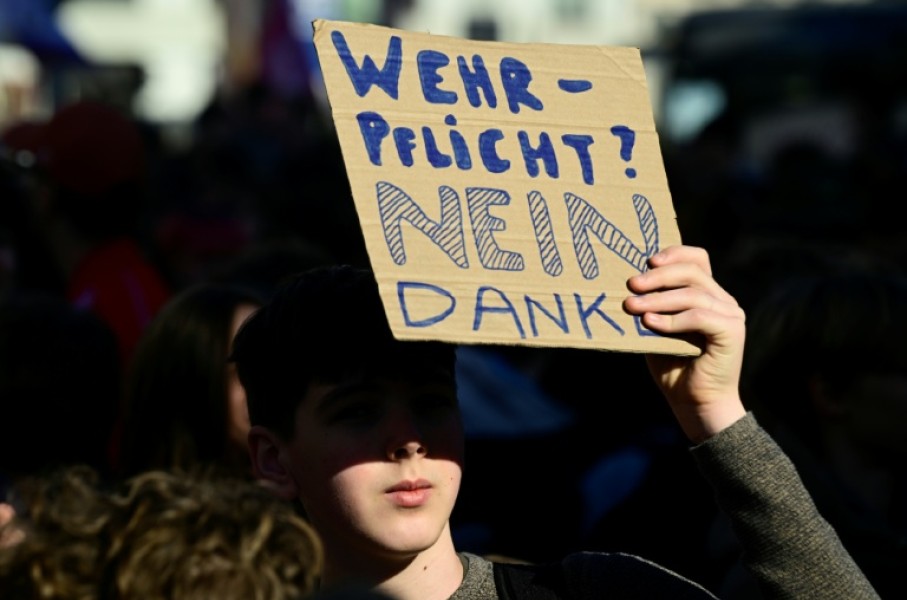 A student holds a sign reading 'Military conscription? No thanks'