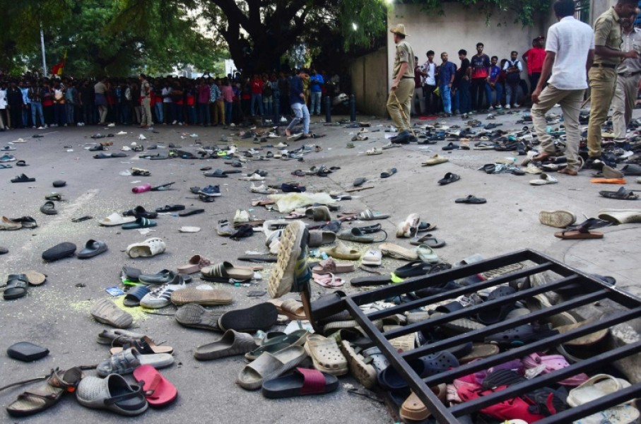 Fans stand next to abandonned shoes and a fallen barrier outside M. Chinnaswamy Stadium
