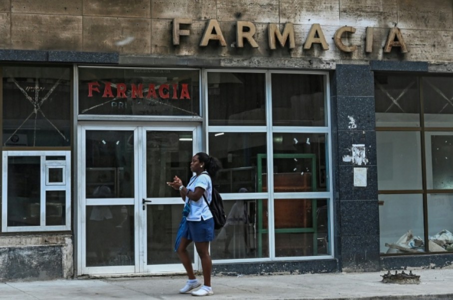 A woman walks past a pharmacy in Havana, where Cuba's communist authorities have announced an opening of sectors of its economy such as petrol stations, medicine sales and electricity generation to the private sector