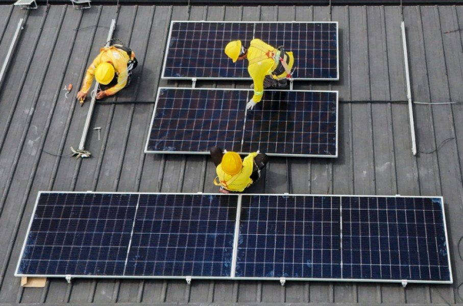 Workers instal solar panels on a roof in Carmona, in the Philippine province of Cavite