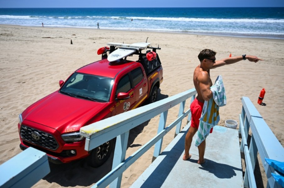 Los Angeles County lifeguard Maximus Oberto gestures as he monitors swimmers in the Pacific Ocean in Manhattan Beach