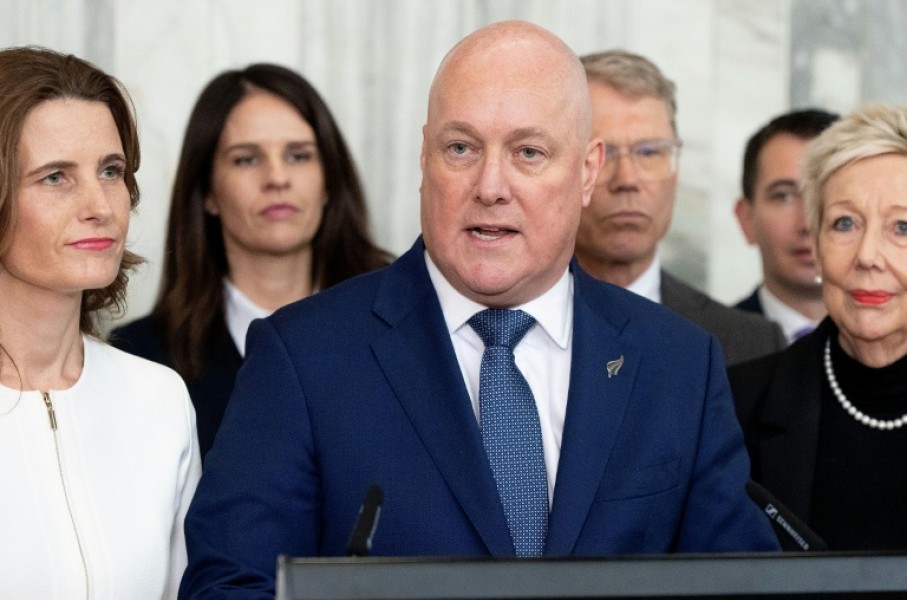 New Zealand Prime Minister Chris Luxon, flanked my his caucus, speaks to the media after surviving a second National party leadership vote at Parliament in Wellington on August 12, 2026