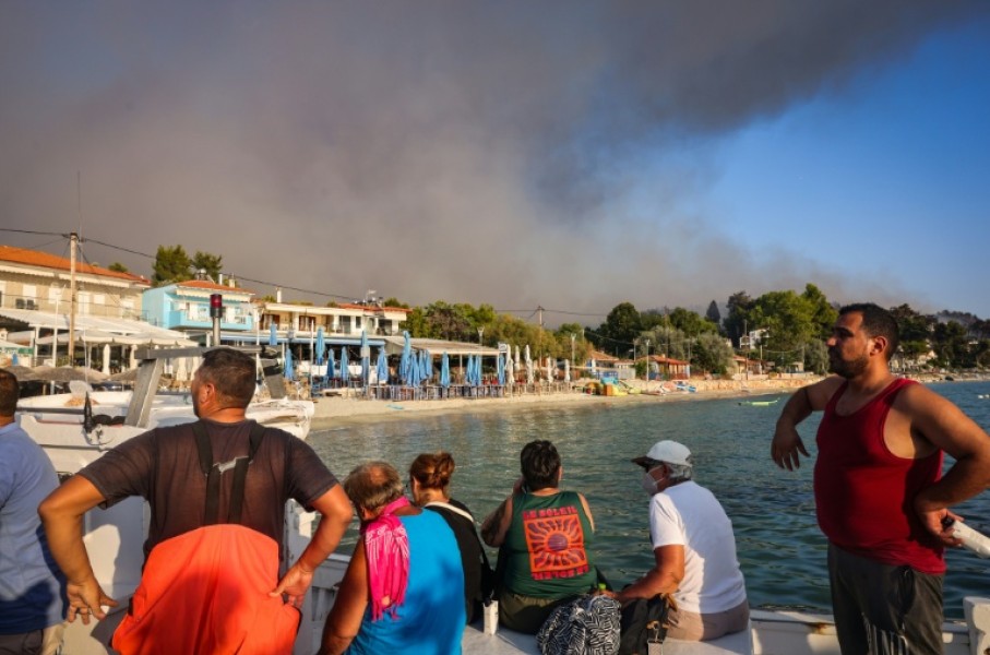 People use small boats to flee a wildfire near the village of Siviri, northern Greece
