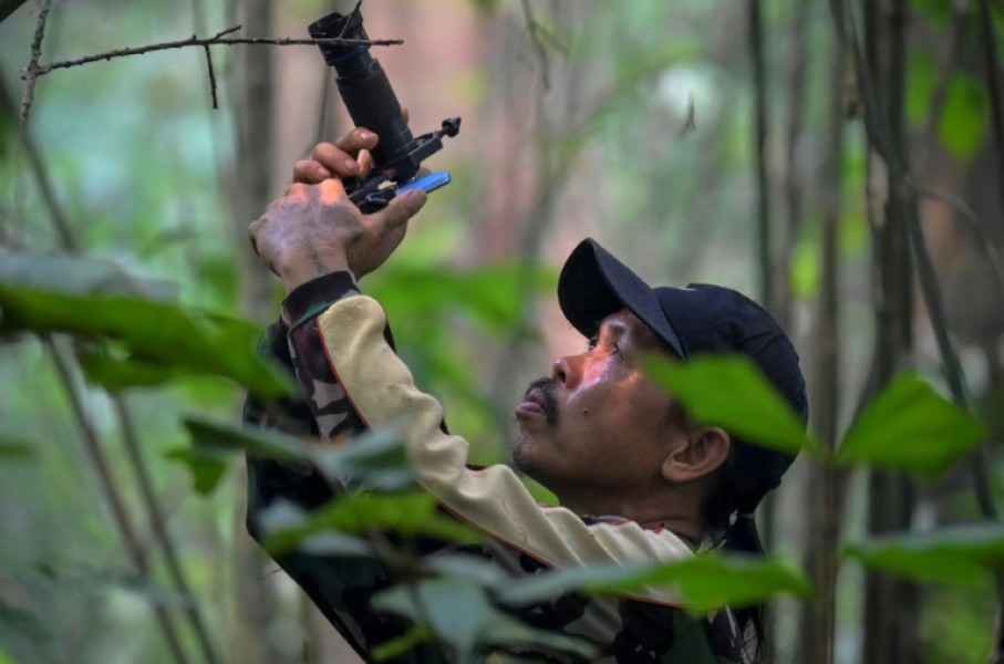 Wildlife observer and former poacher Octavius using a mobile phone equipped with a telephoto lens to take pictures of wildlife in a forest near Labian village in Kapuas Hulu, West Kalimantan