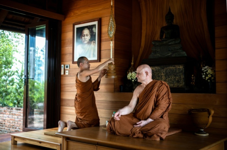 British and Thai Buddhist monk Shaun Chiverton, now known as Ajahn Jayasaro, sits as another monk holds a ceremonial fan in Bangkok
