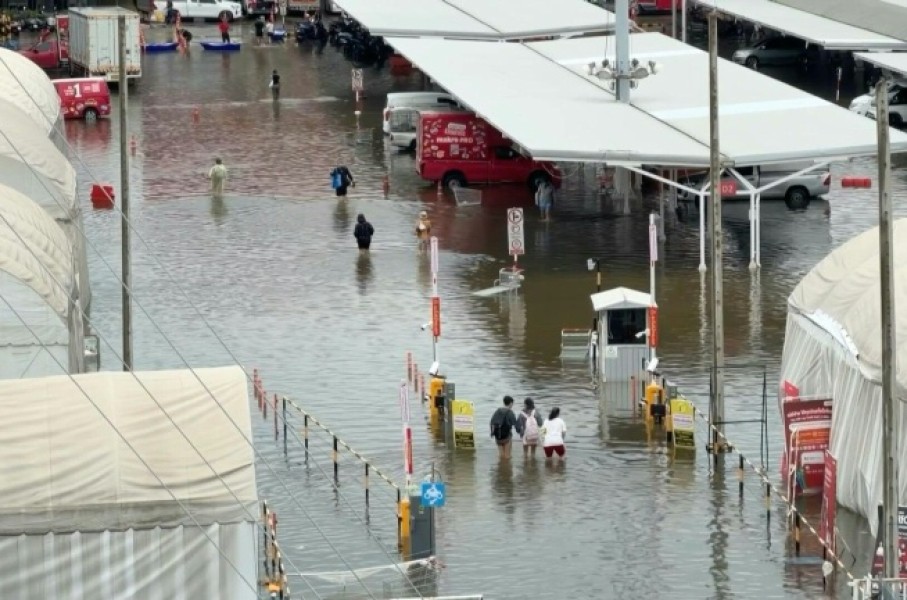 Pedestrians wade through flooded Bangkok roads after days of rain