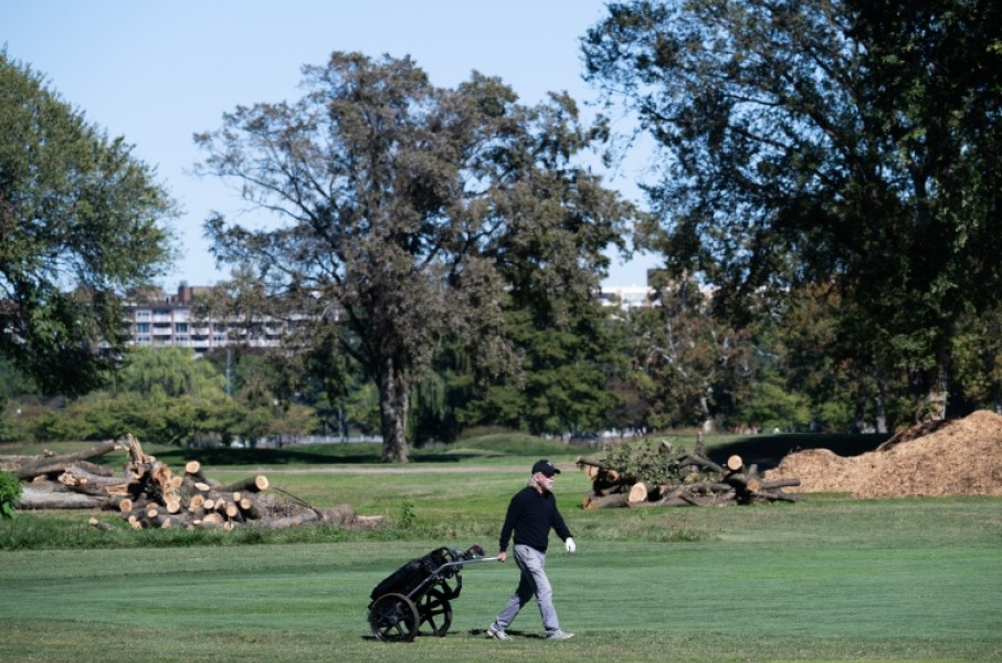 A golfer walks on the course in front of cut down trees at East Potomac Golf Links in Washington DC