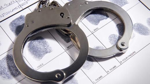 File: Handcuffs laying on top of fingerprint chart. GettyImages/TheCrimsonRibbon