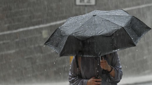 File: A person uses an umbrella to shelter from the heavy rain. AFP/Peter Parks