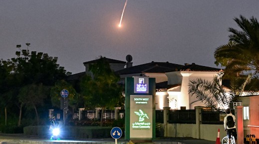 A cyclist watches as a projectile falls over Dubai. AFP