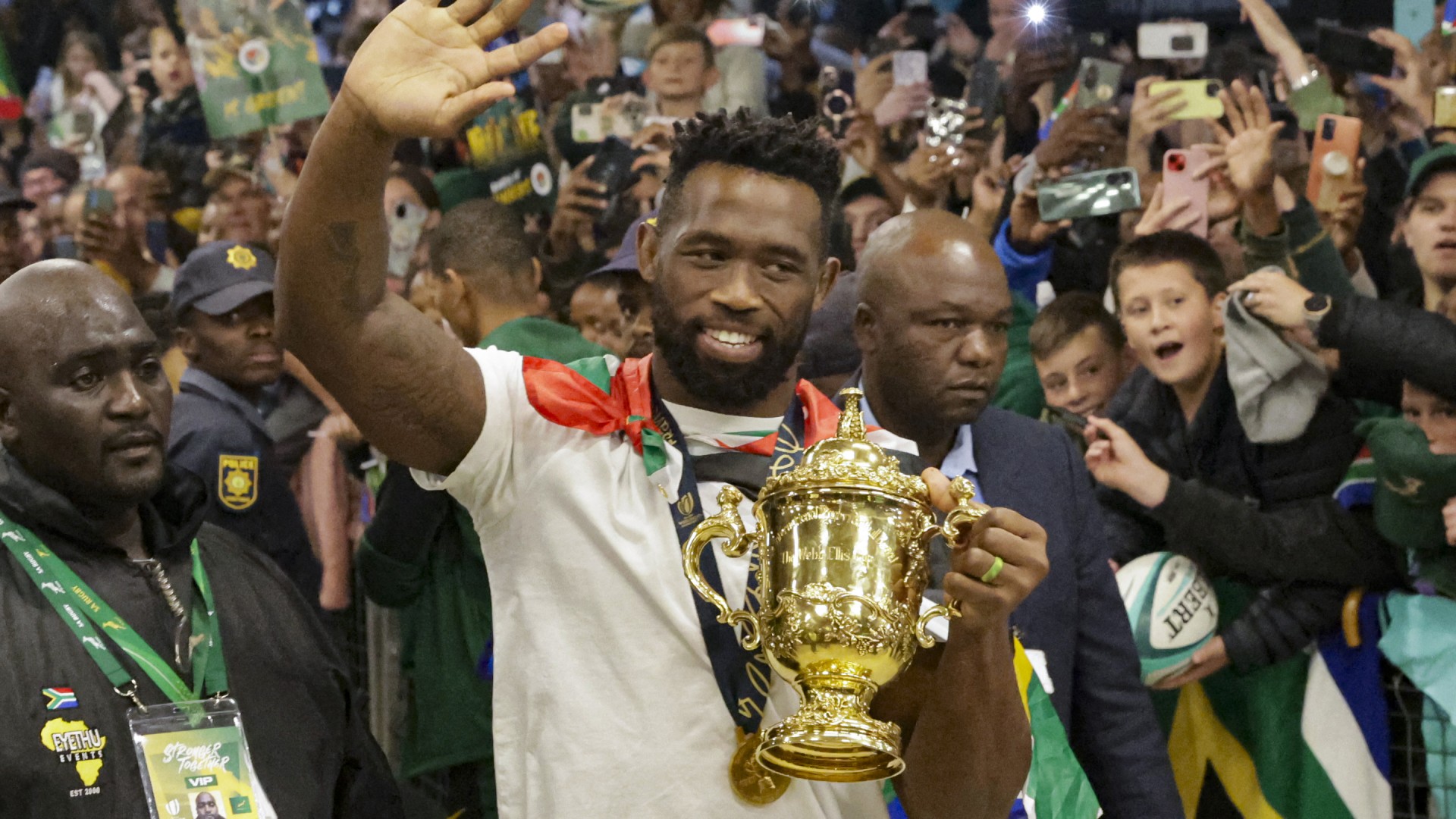 South Africa's flanker and captain Siya Kolisi waves at supporters as he holds the Webb Ellis Cup upon the South African rugby team's arrival at the OR Tambo International airport in Ekurhuleni on October 31, 2023, after they won the France 2023 Rugby World Cup final match against New Zealand.