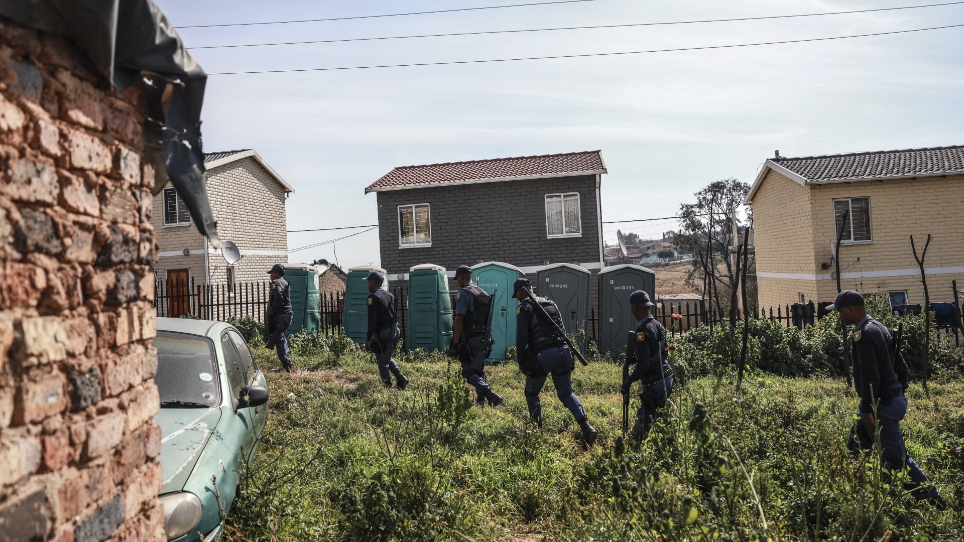 South African Police Service (SAPS) officers walk during raid to retrieve looted goods during a protest at Diepkloof Hostel in Soweto on May 19, 2025.