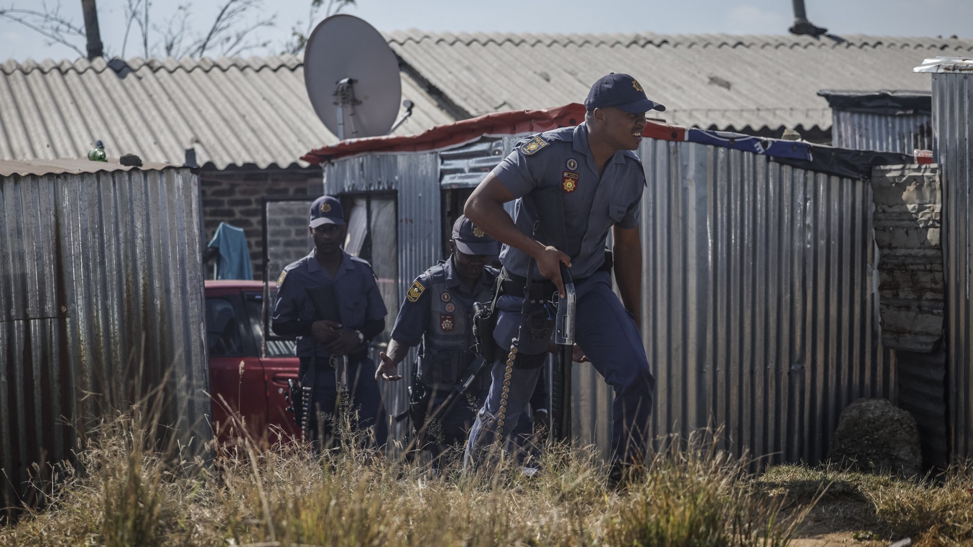 South African Police Service (SAPS) officers walk during a raid to retrieve looted goods during a protest at Diepkloof Hostel in Soweto on May 19, 2025.