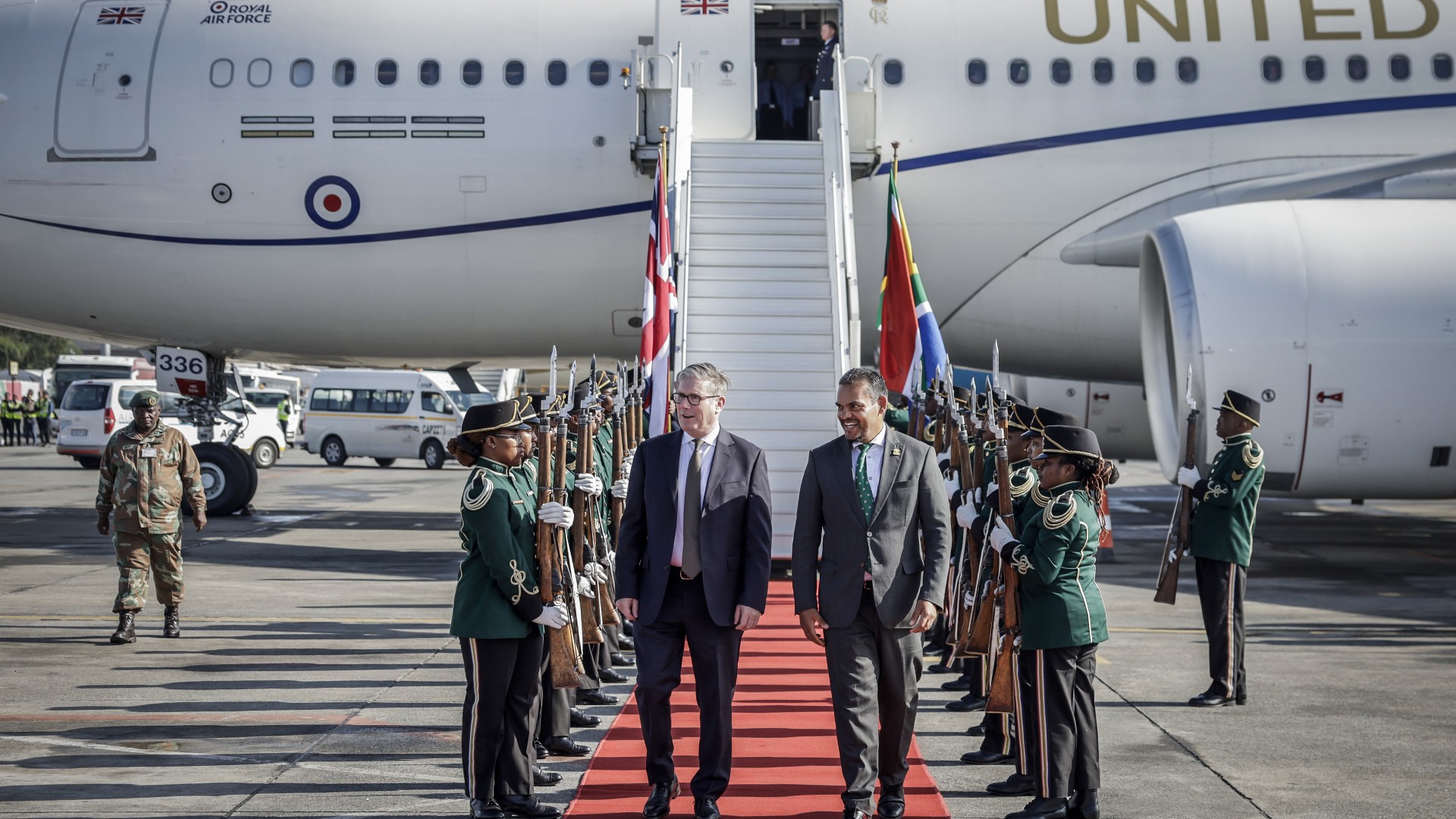 Britain's Prime Minister Keir Starmer (C-L) is welcomed by a South African representative upon his arrival at OR Tambo International Airport in Ekurhuleni on November 21, 2025 ahead of the G20 leaders' Summit.