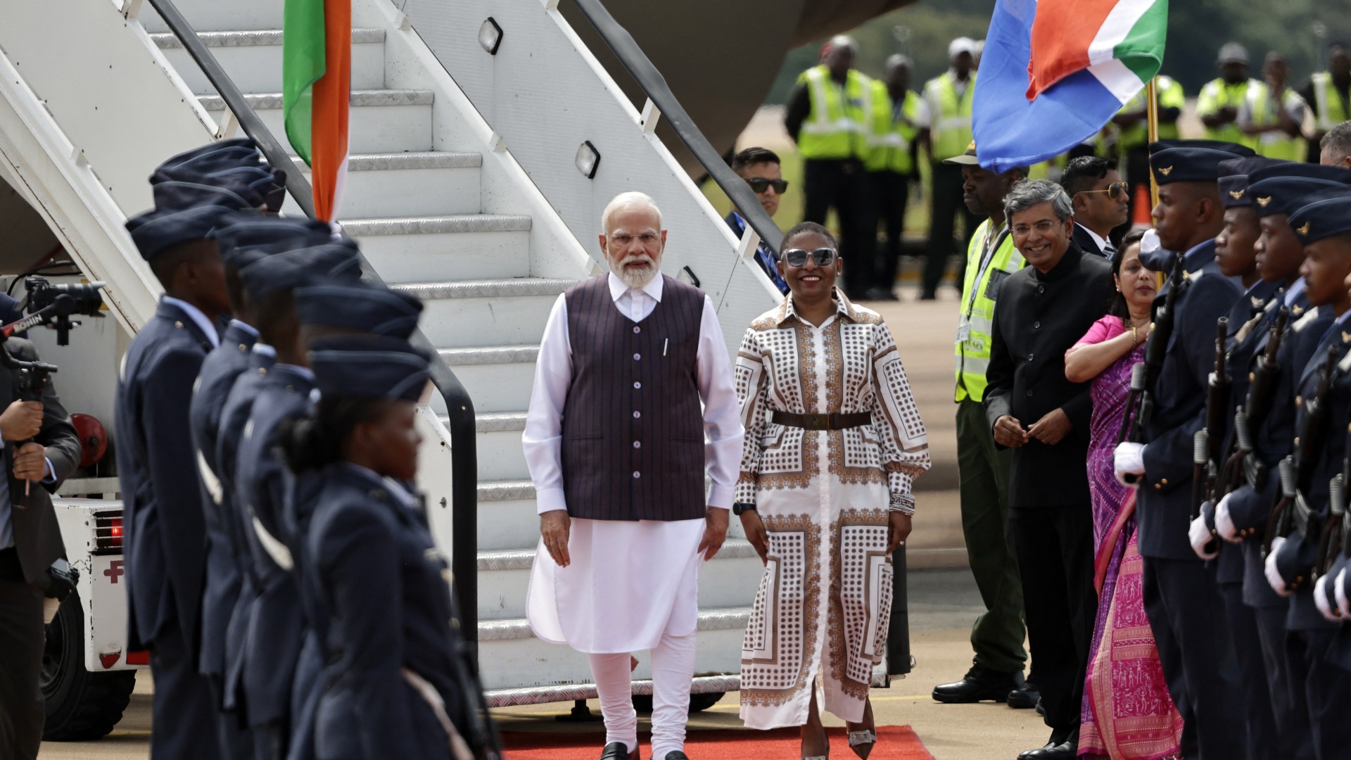 India's Prime Minister Narendra Modi (C-L) is welcomed by Minister in the South African Presidency Khumbudzo Ntshavheni (C-R) upon his arrival at the Air Force Base Waterkloof in Pretoria, on November 21, 2025 ahead of the G20 leader's Summit.